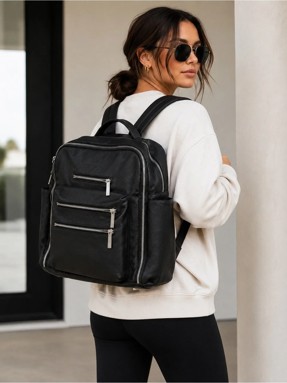 The Honest Company Black Vegan Leather Diaper Bag backpack model cross country